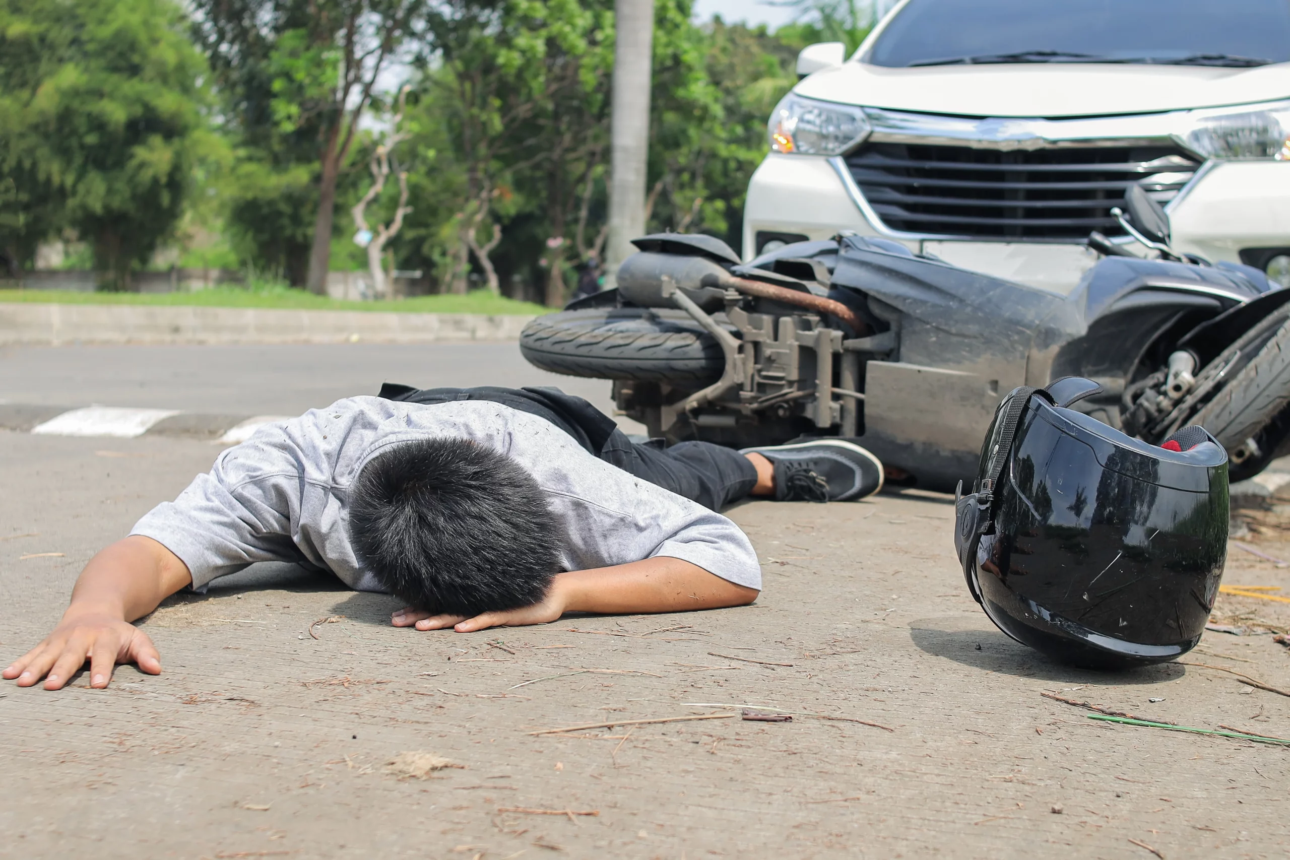 Injured motorcyclist after a motorcycle accident in Austin, Texas with a damaged car nearby