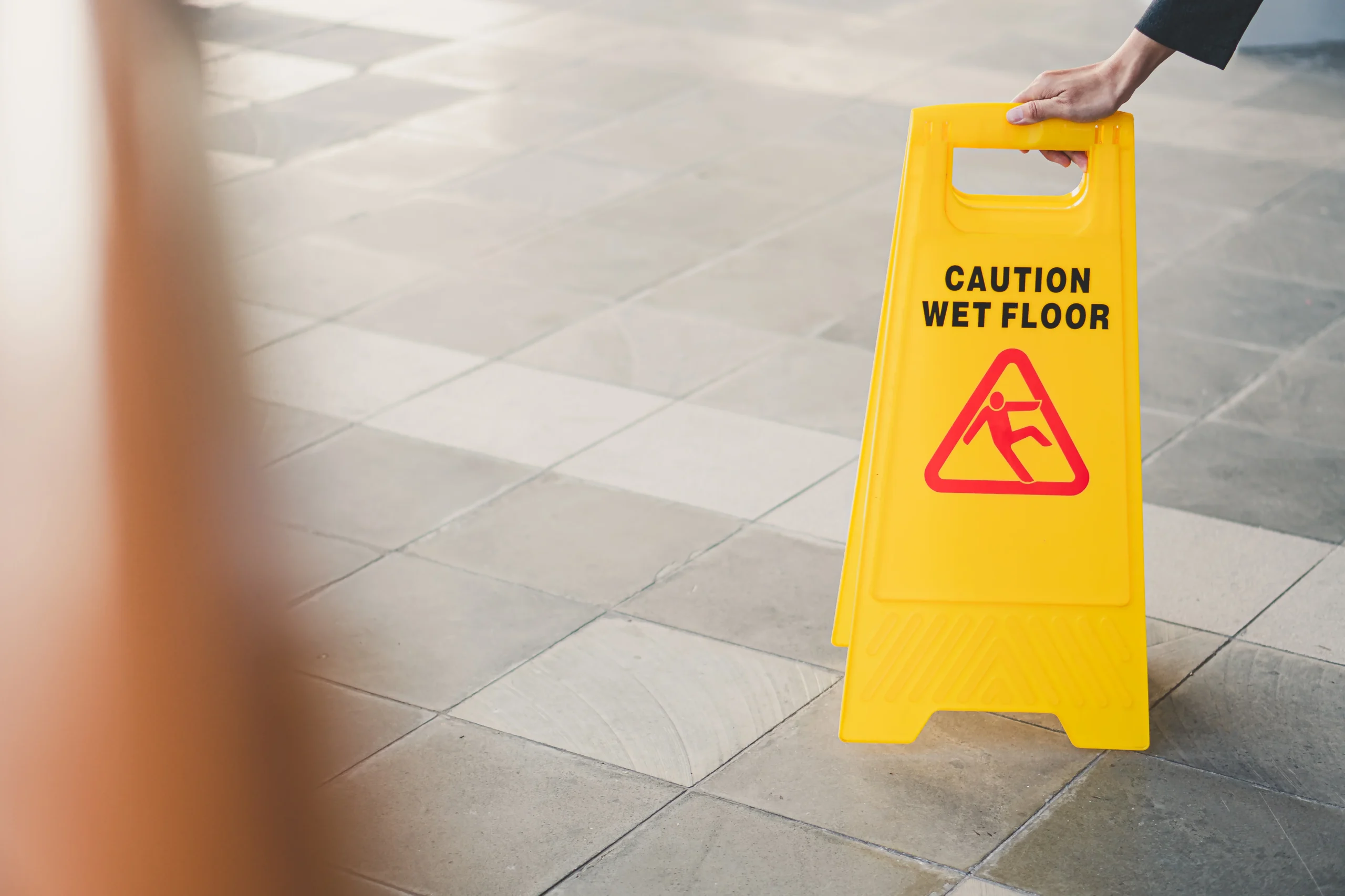 Wet floor warning sign highlighting slip and fall liability in Texas